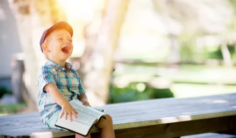 boy sitting on bench while holding a book
