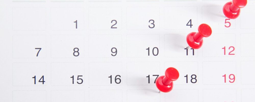a calendar with red push buttons pinned to it